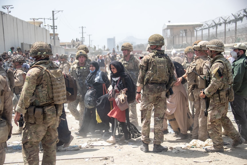 Women in hijab walk through a cordon of soldiers in the midst of a crowd