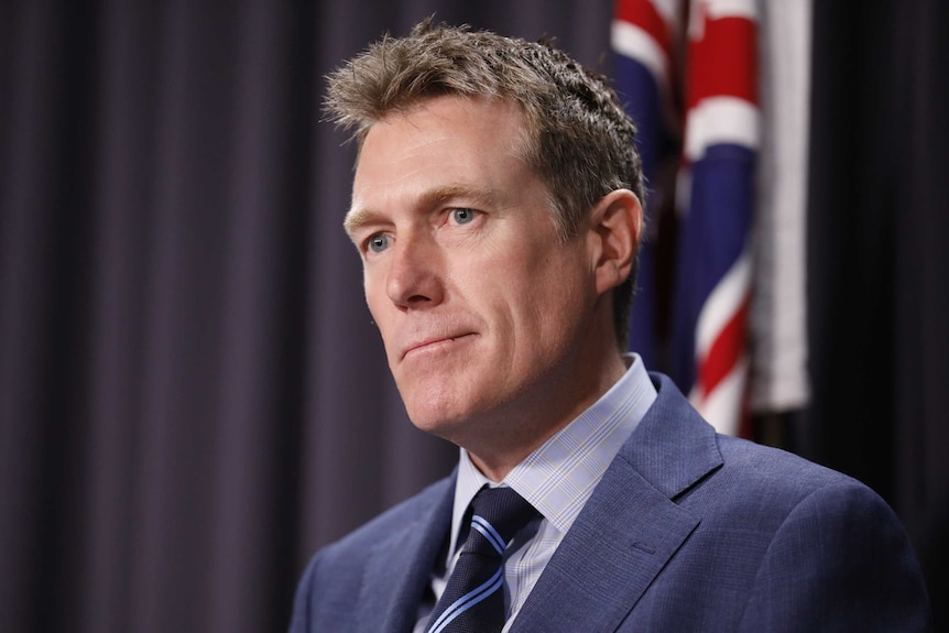 Christian Porter stands in front of an Australian flag