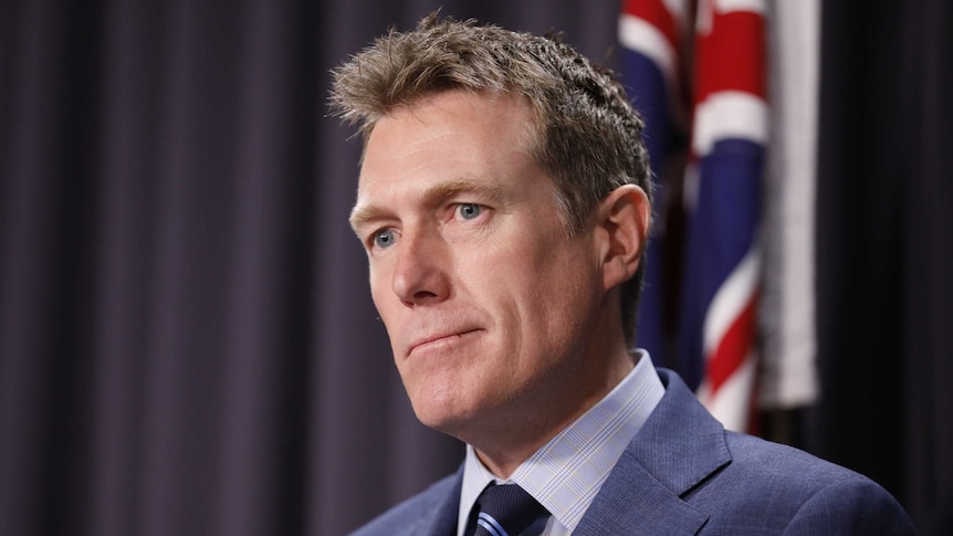 Christian Porter stands in front of an Australian flag