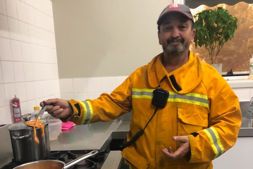 A CFA volunteer making spaghetti on the stove in the Walwa Bush Nursing Centre while looking at the camera.