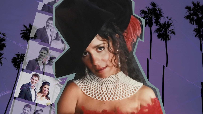A woman in a large black hat and white necklace looking curiously at the camera.