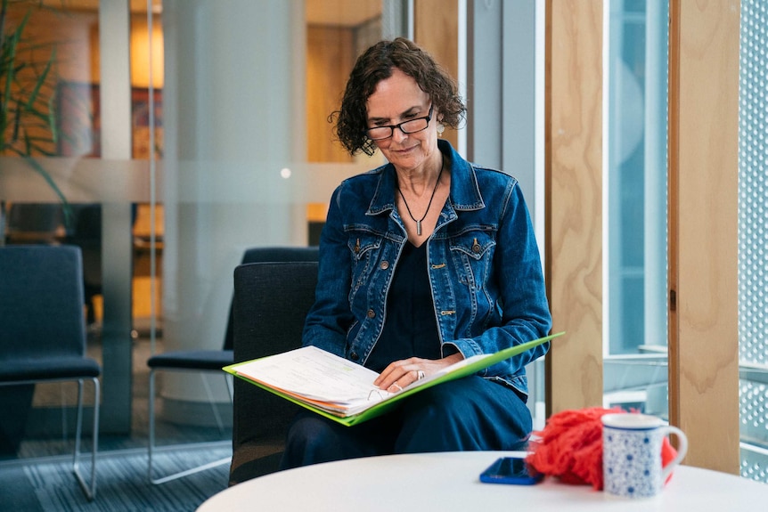 Andrea Hammond sits and looks at a folder of documentation.