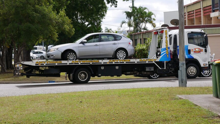 a small silver car is being towed away