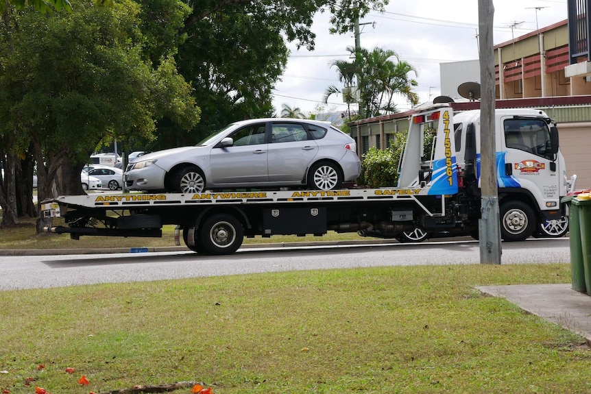 a small silver car is being towed away