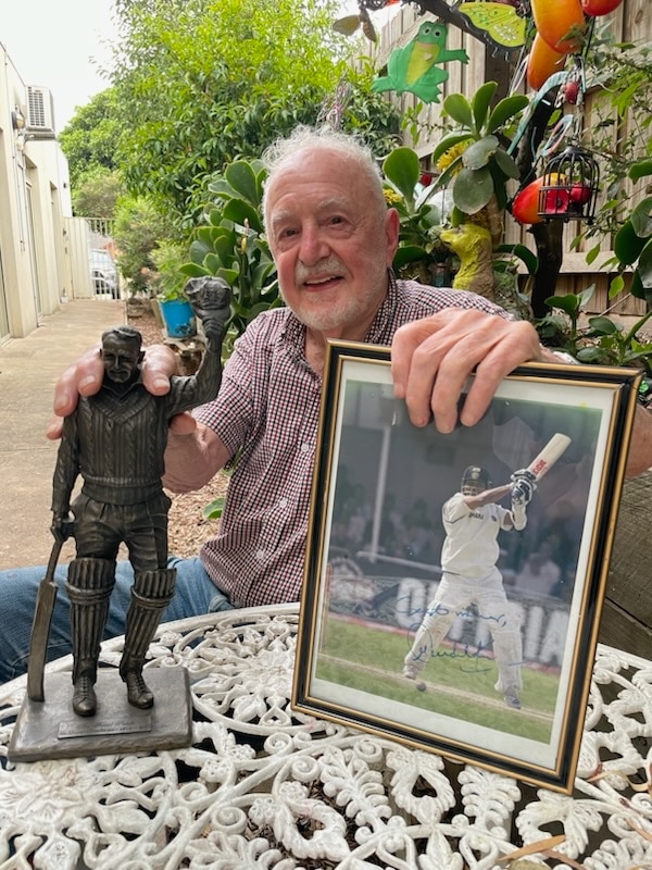 An older man with a statue and a photo.