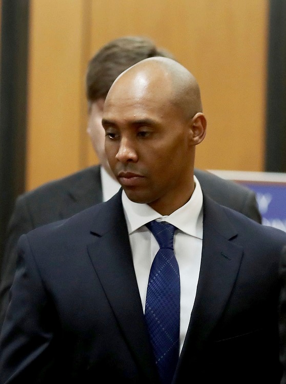 Two men in suits look away from the camera as their picture is taken while they walk towards a courthouse.