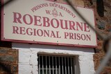 Roebourne Regional Prison sign seen through a fence. 