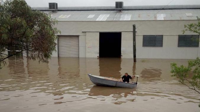 A man in a boat makes his way through floodwaters in Chinchilla.