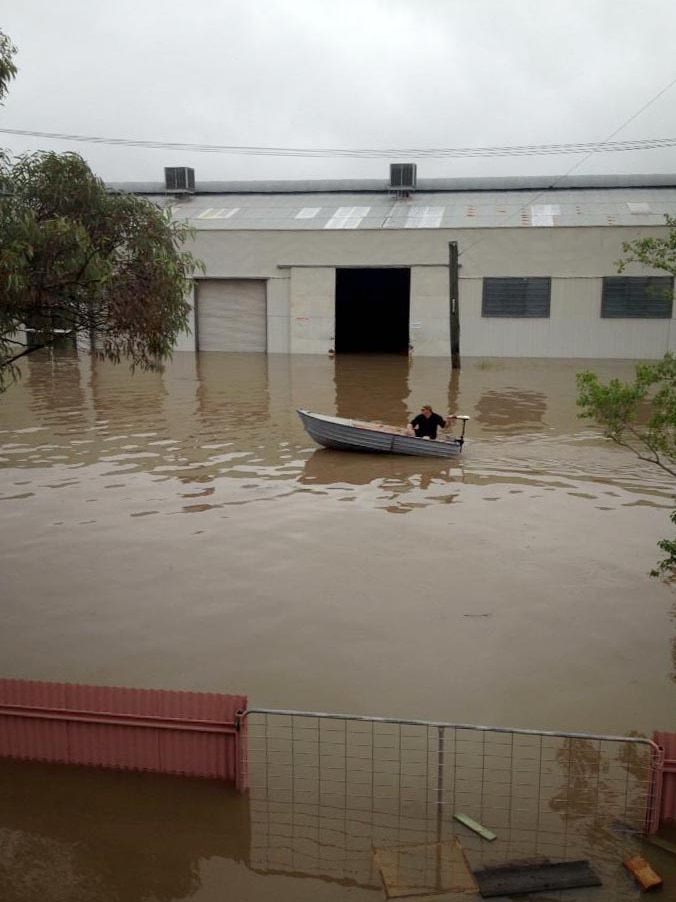 A man in a boat makes his way through floodwaters in Chinchilla.