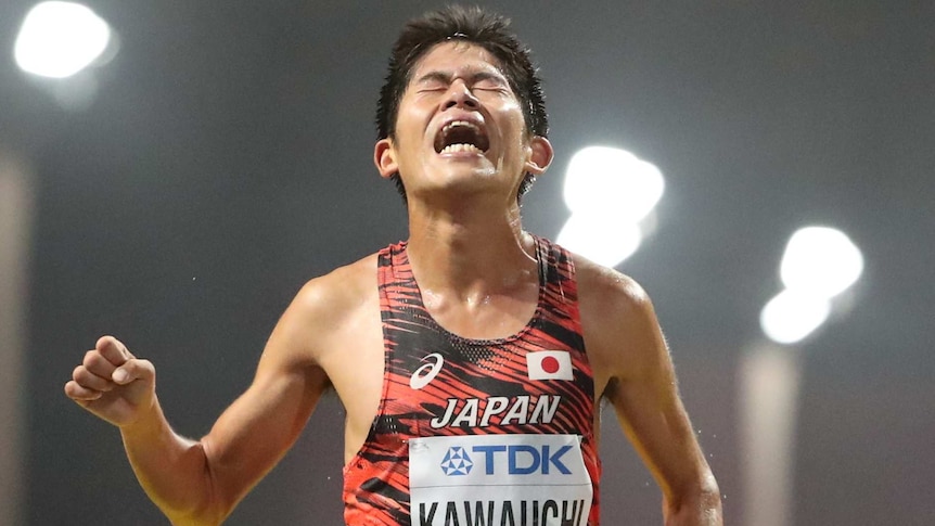 A Japanese man crosses the finish line of a marathon.