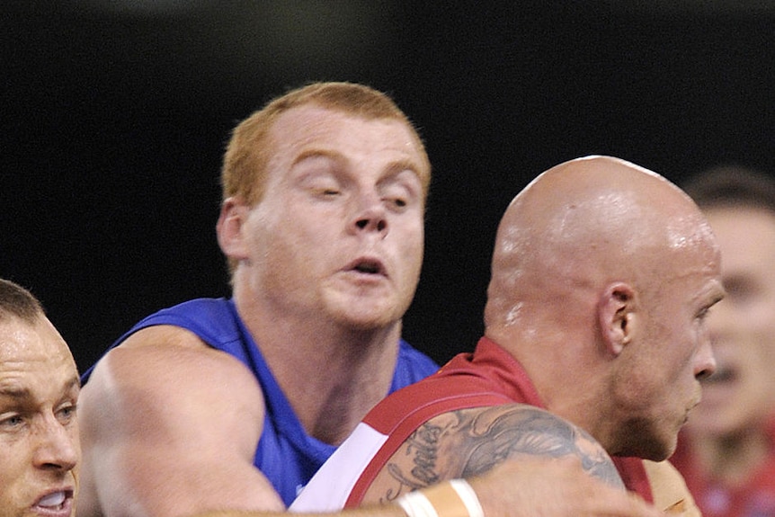 Western Bulldogs Daniel Cross (L) and Adam Cooney (2nd L) tackle Melbourne's Nathan Jones in 2011.