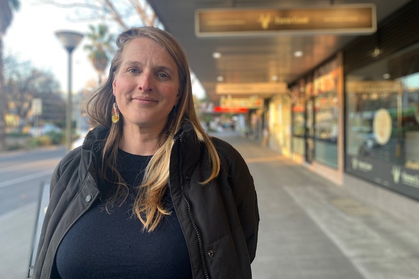 A woman stands in a shopping mall on the street.