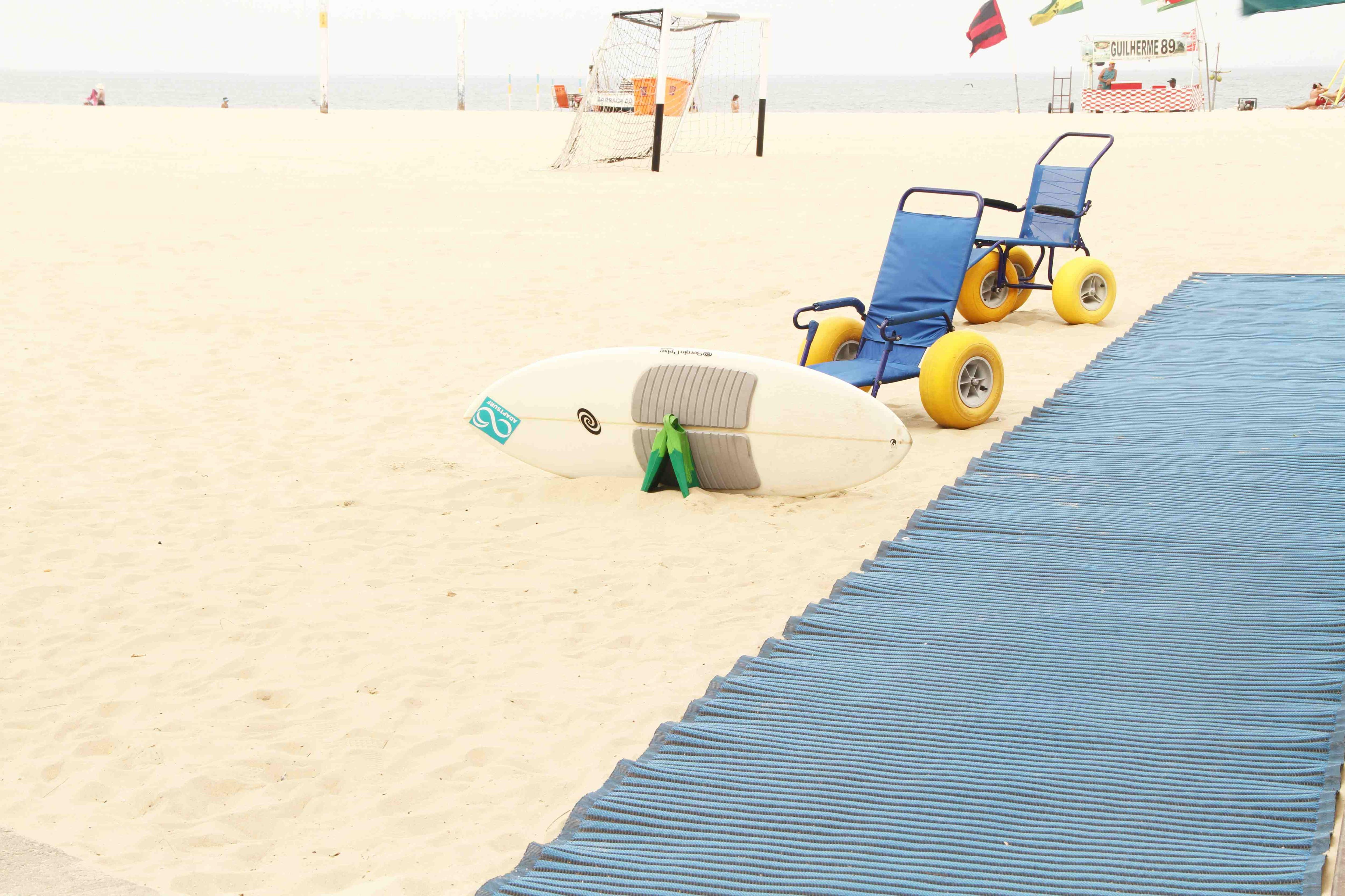 Una playa de arena con un camino de esteras azules y sillas de ruedas impermeables.