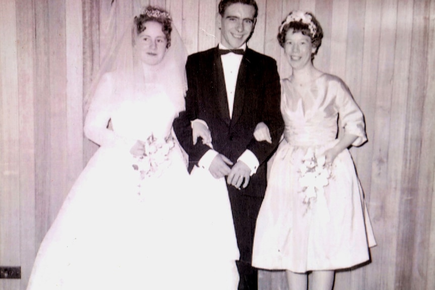 A man in a suit stands next to a bride and another woman at a 1960s wedding