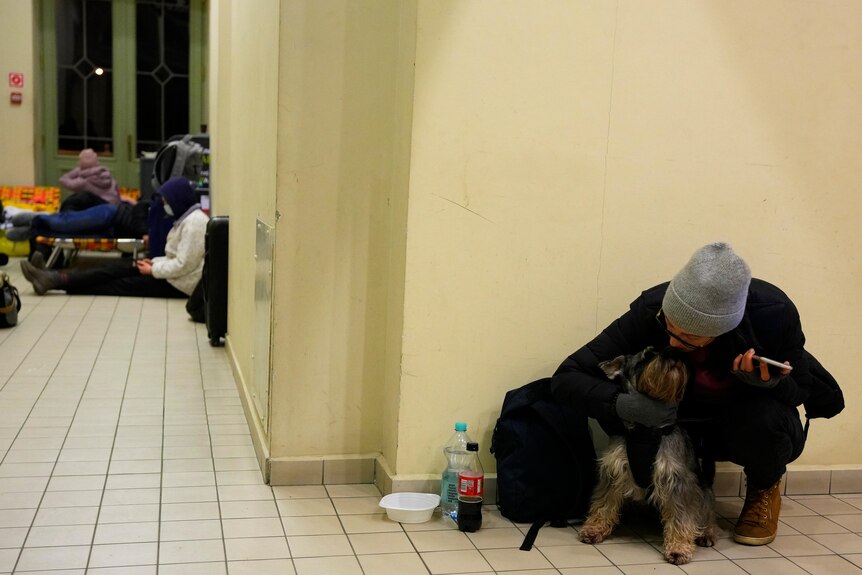 Ukrainian woman holds her dog while sitting at a train station turned into an accommodation centre