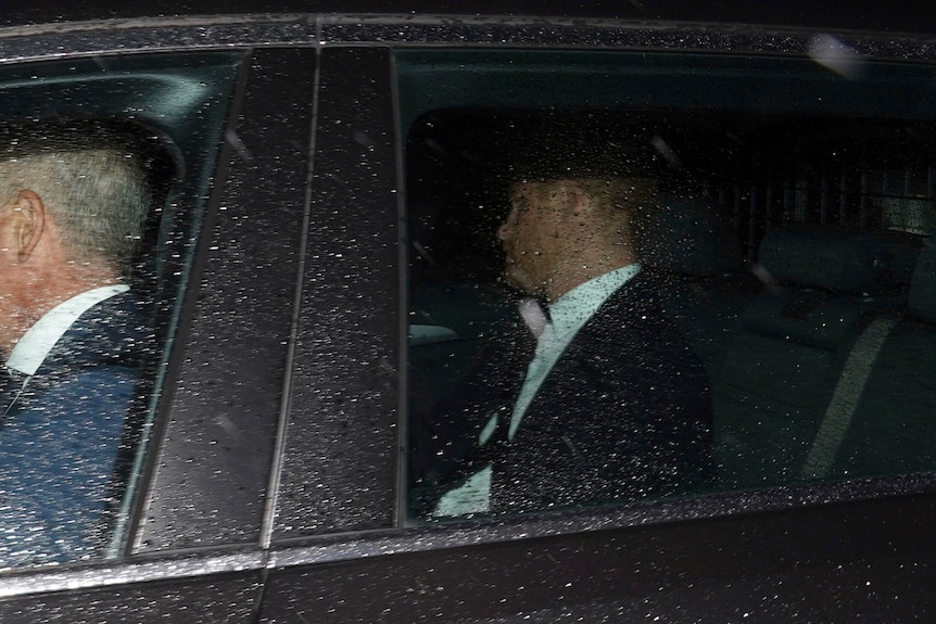 El príncipe Harry en la foto trasera de un auto negro.  Gotas de lluvia que cubren la ventana.