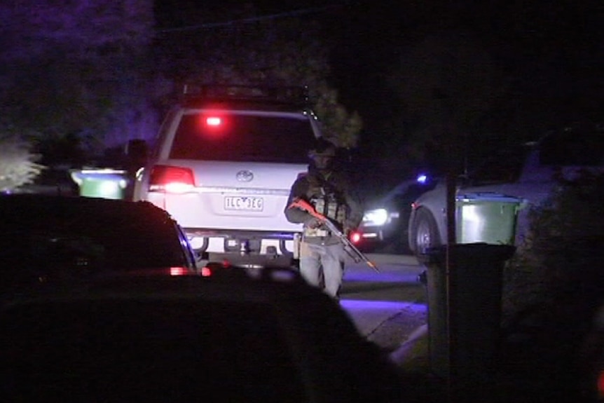 A police officer holds a gun at the scene of a siege in Rosebud.