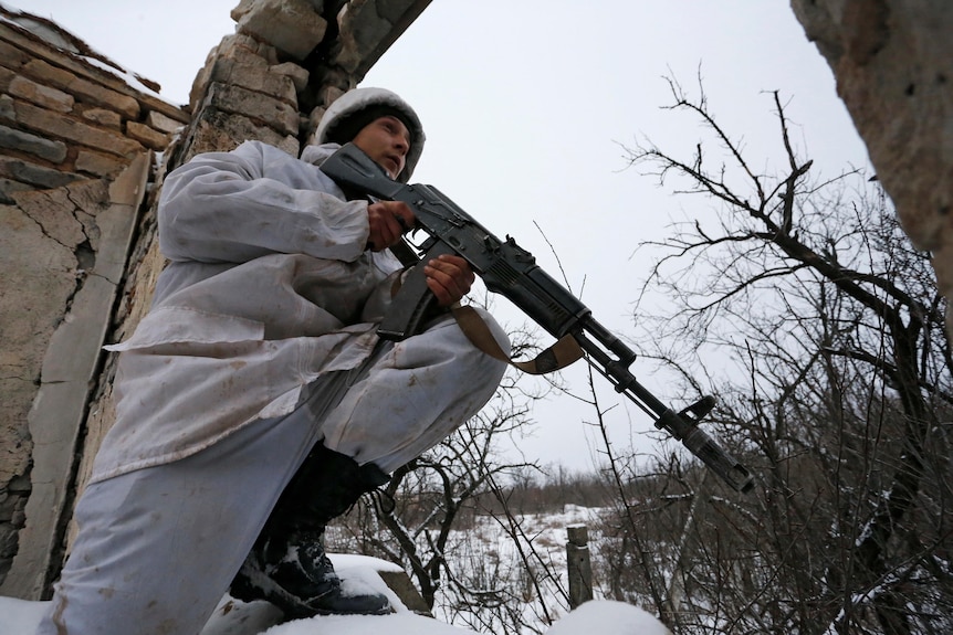 A man in white camouflage holds a rifle.