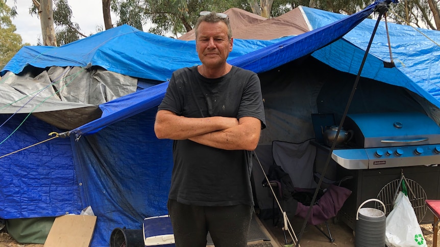 a man stands in front of his tent