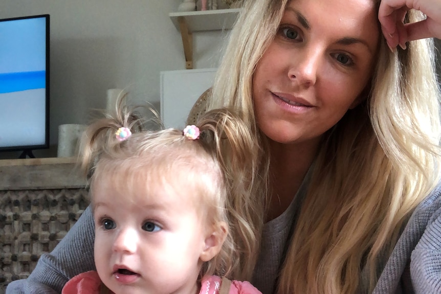 A woman with long blonde hair and a toddler with blonde pigtails