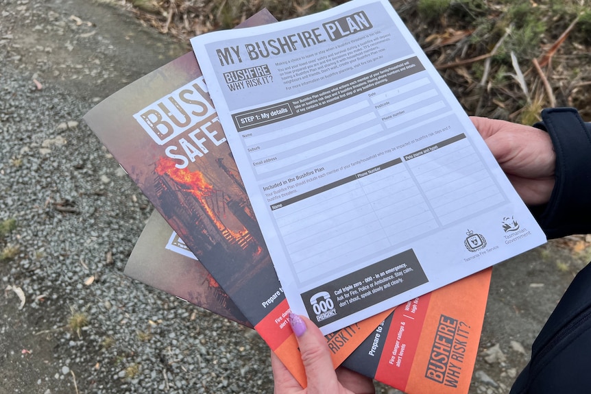 Hands holding three Tasmania Fire Service bushfire safety plan documents