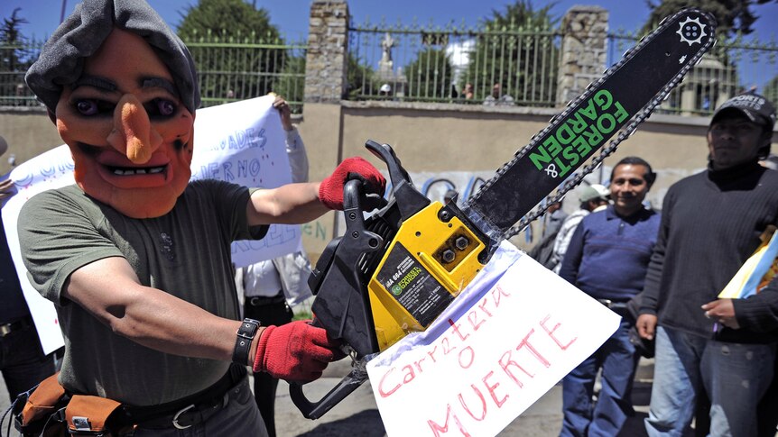 A man wearing a mask of Bolivian president Evo Morales holds a chainsaw during a protest in in support of the Amazon natives