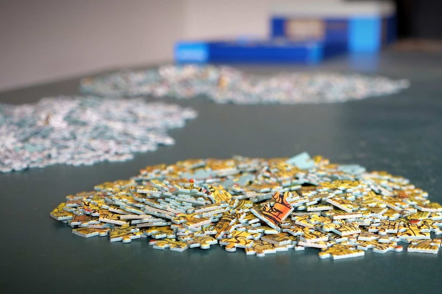 Several piles of puzzle pieces, separated according to colour