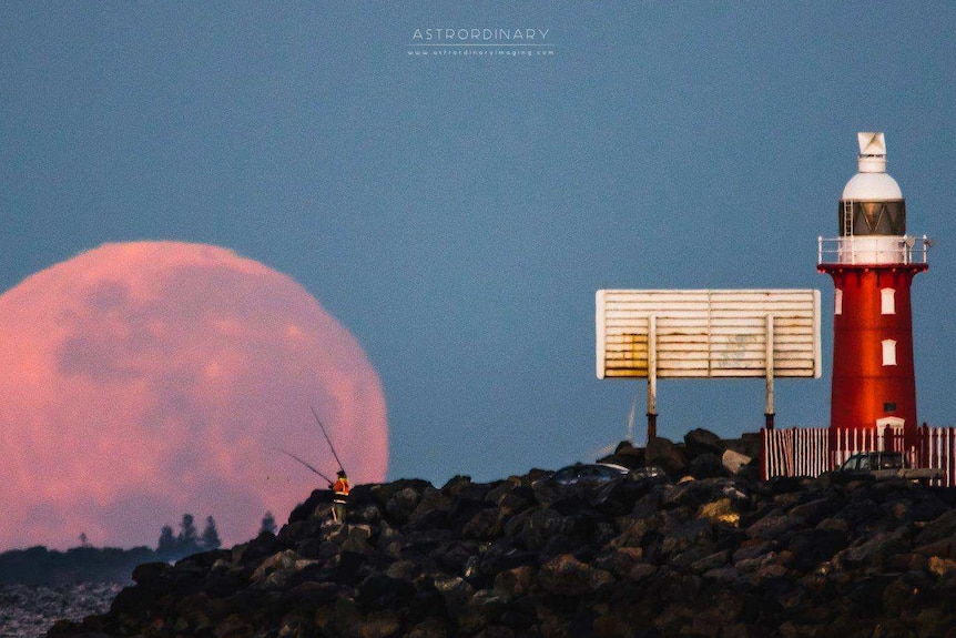 A supermoon rises at North Mole in Fremantle with a lighthouse and fishermen in the foreground