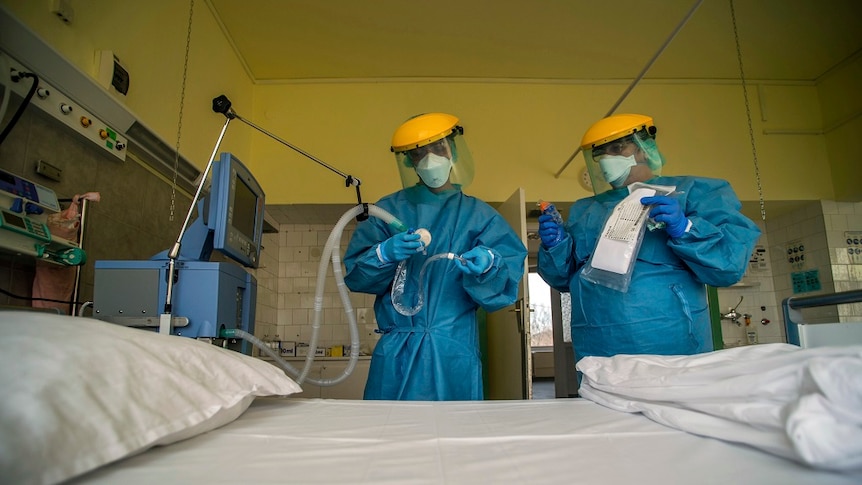 Two medical staff member checking a ventilator.