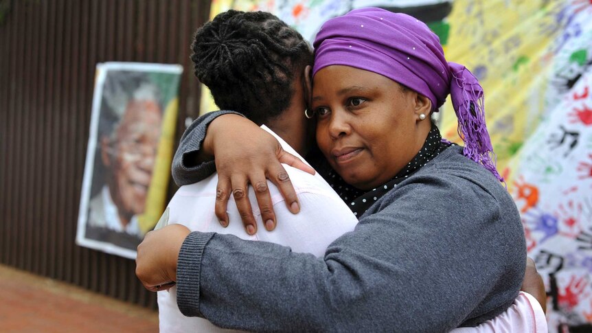 Two women console each other outside on Vilakazi Street in Soweto