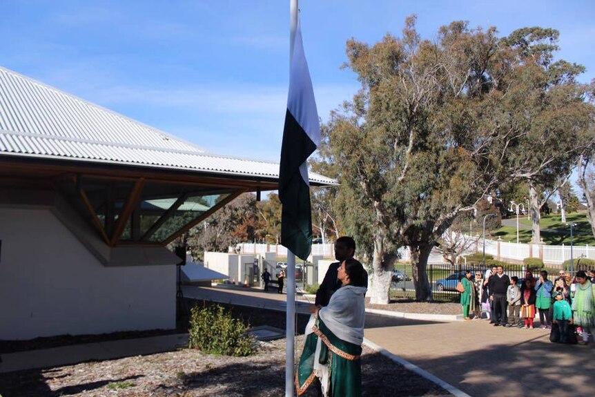 Naela Chohan and an unidentifiable male are seen hoisting a flag outside the embassy