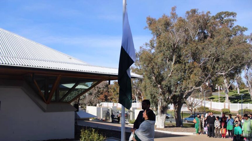 Naela Chohan and an unidentifiable male are seen hoisting a flag outside the embassy