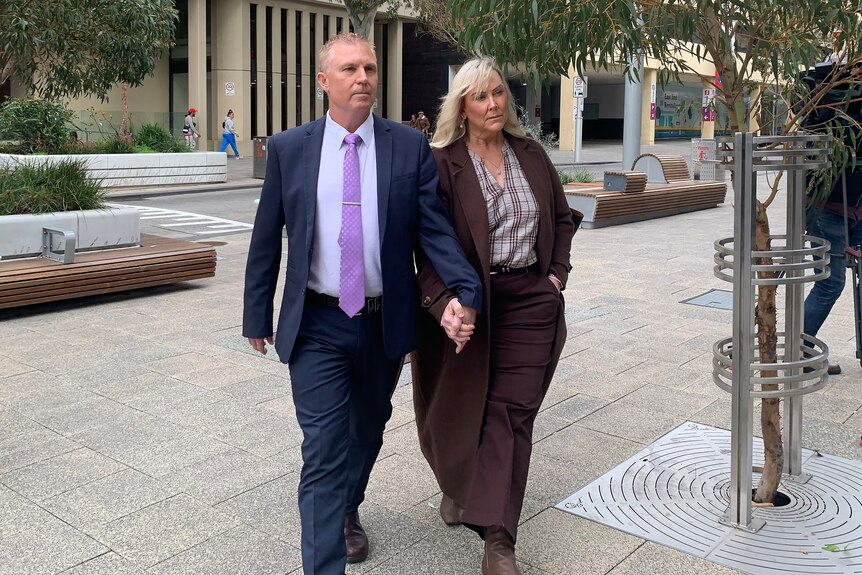 A mid shot of WA Upper House MP James Hayward arriving at court wearing a blue suit, white shirt and purple tie.