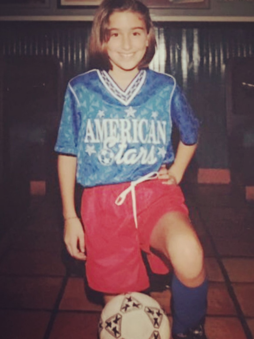 Young soccer player stands on the ball