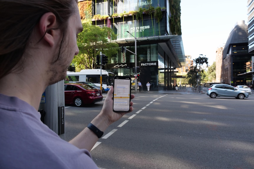 A man holding a phone at a busy traffic intersection