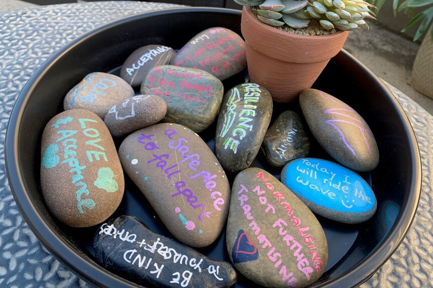 Rocks painted with messages of hope and understanding, sitting in a bowl.