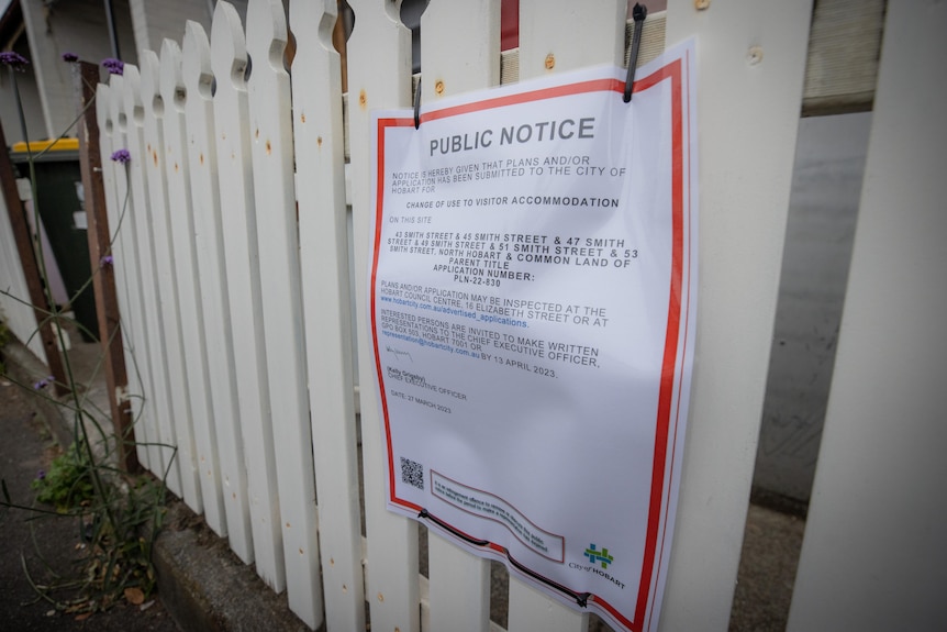 A white sign with red border on a  fence