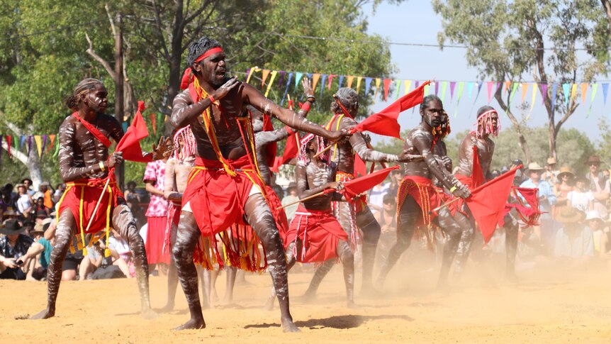 Indigenous dancers putting on a show in the red dirt.
