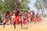 Indigenous dancers putting on a show in the red dirt.