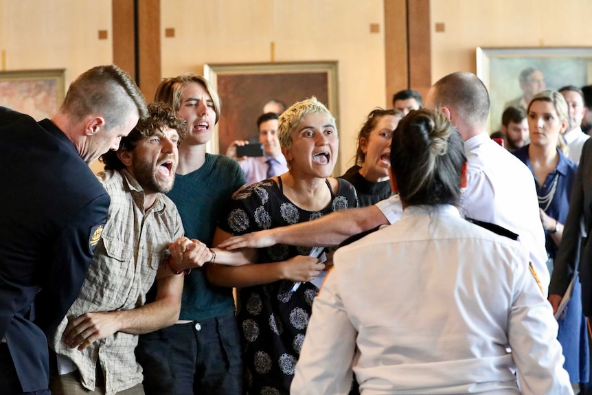 A group of protesters yell at security guards in Parliament House.