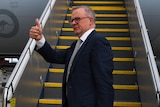 Albanese gives a thumbs up from the tarmac in front of a plane