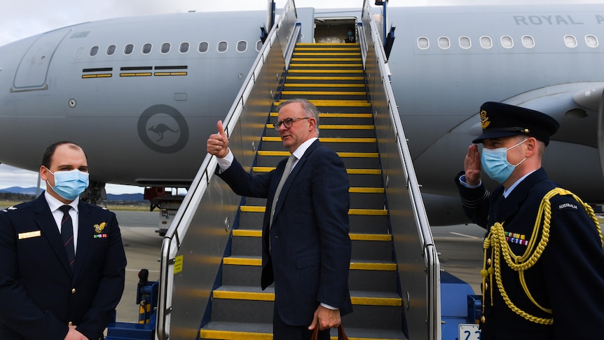 Albanese gives a thumbs up from the tarmac in front of a plane