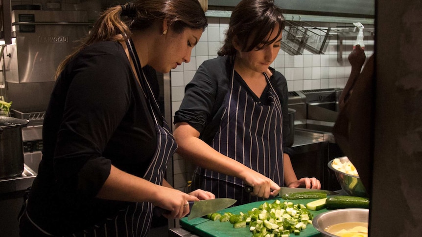 Two women chopping cucumbers