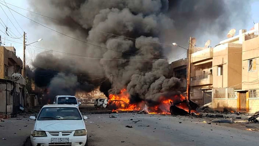 Black plumes of smoke come off burning cars.