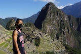 Man wearing black mask and basketball journey stands at Machu Picchu