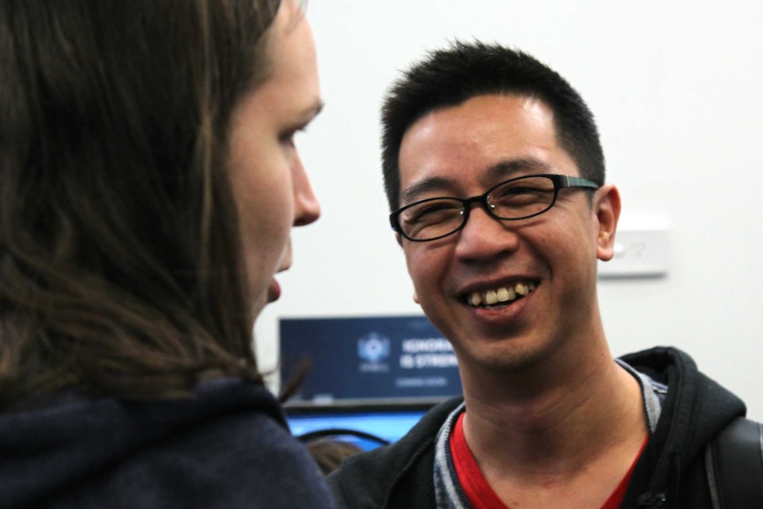 Henry Fong having a conversation with someone and laughing.