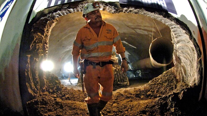 A construction worker walks through an underground tunnel, which is under construction.