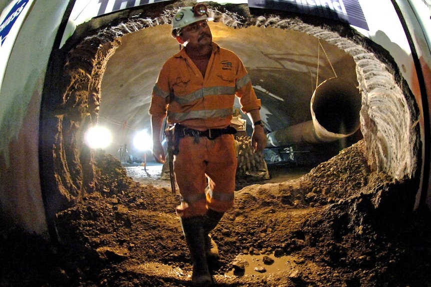 A construction worker walks through an underground tunnel, which is under construction.