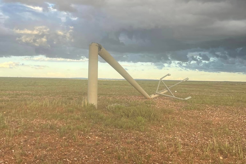 An image of a broken down power pole on the ground surrounded by clouds