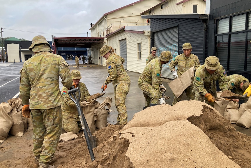 A group in army fatigues shovels sand into bags